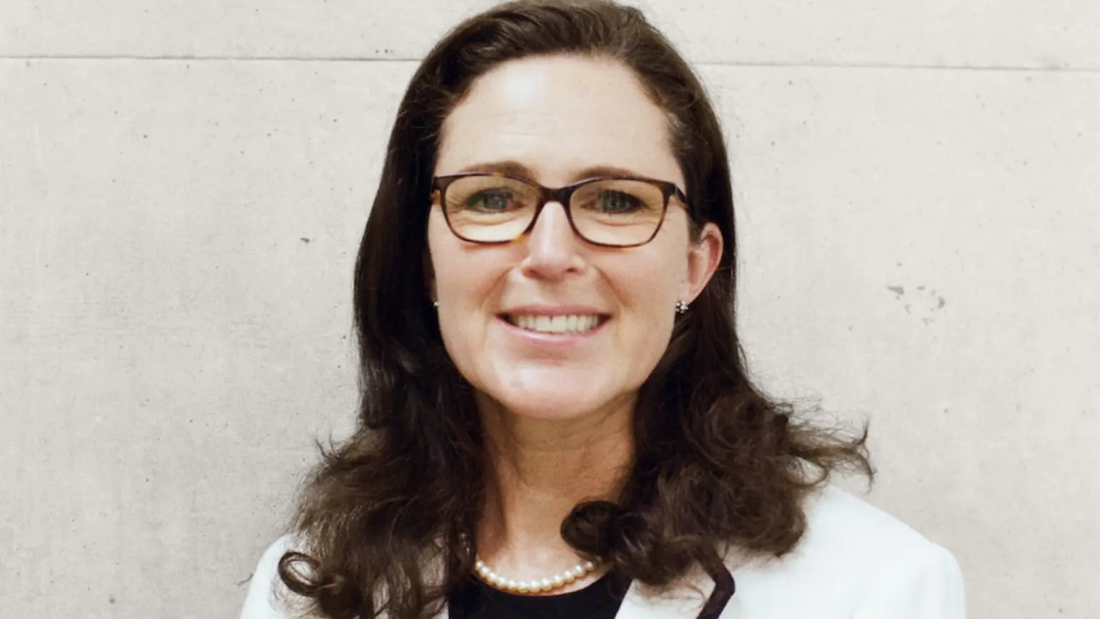 Headshot of Antonia Jenkinson standing in front of a white wall