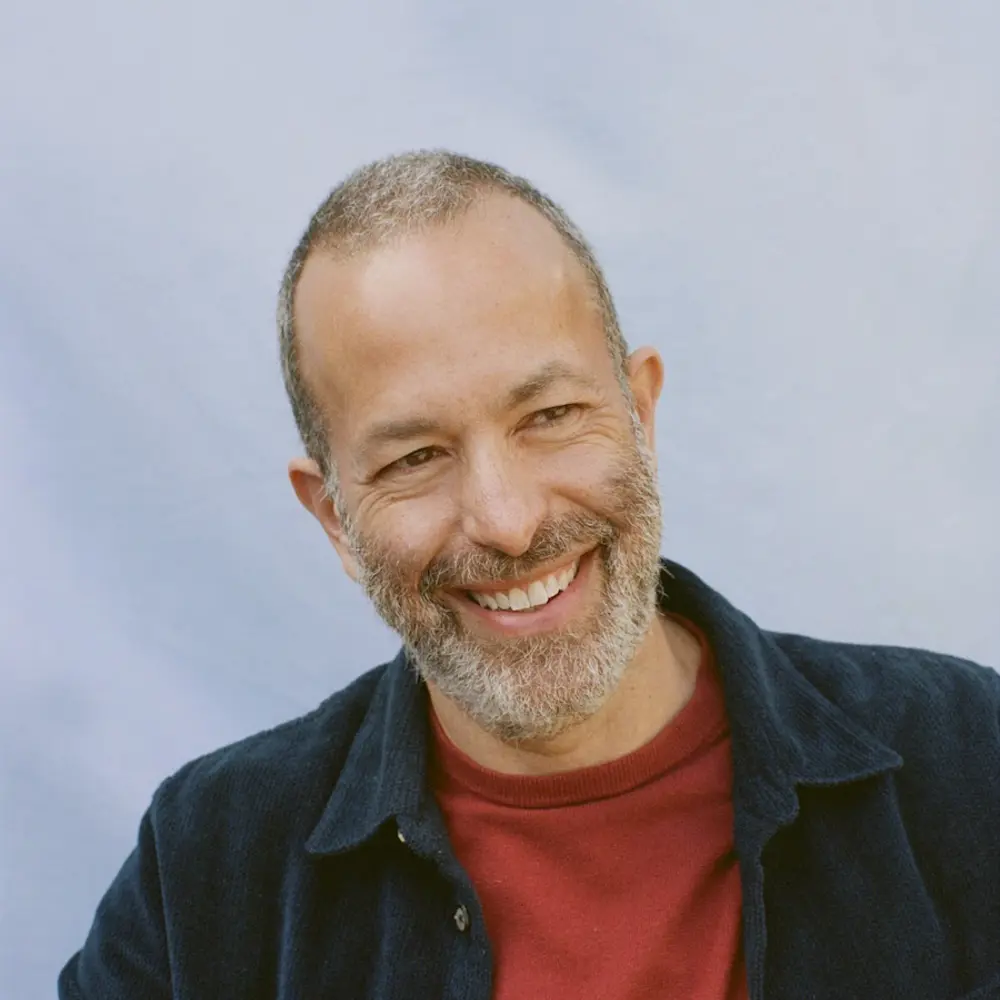 Photo of Nathan Wolfe smiling, against a blue background