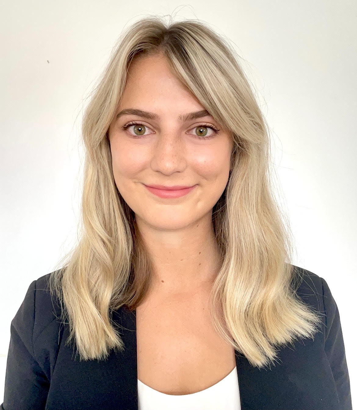 Photo of Caitlyn Kubala standing against a cream wall