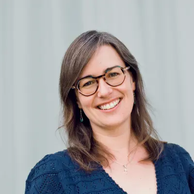 A picture of Angie Burnett smiling against a blue curtain background.