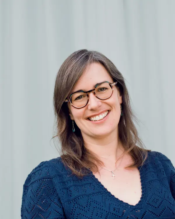 A picture of Angie Burnett smiling against a blue curtain background.