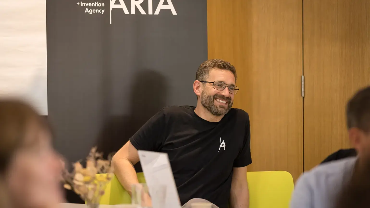 A man sitting and smiling at a table during a workshop
