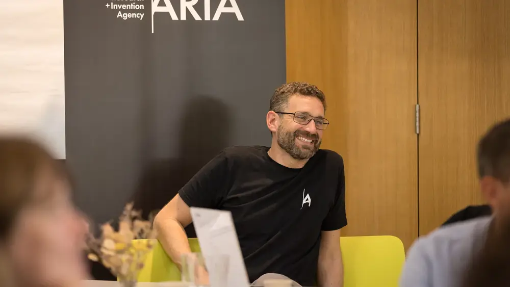 A man sitting and smiling at a table during a workshop