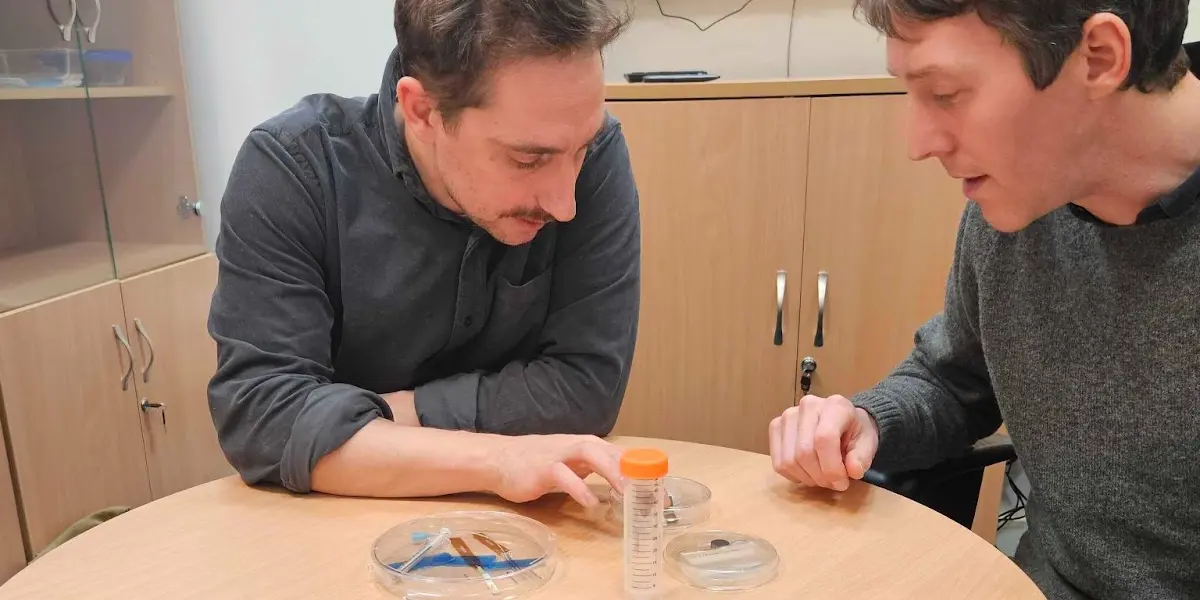 A photo of Jacques and another person looking at items on a table.