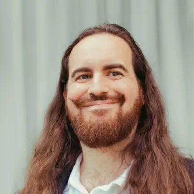 A photo of davidad smiling in front of a blue background.